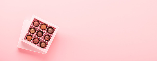 Chocolate truffle candies in a box pink background. Gifts festive food love concept. Horizontal frame copy space banner. © ximich_natali