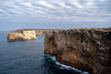 Fototapeta na wymiar Rocky cliffs and shoreline at Cabe De Sao Vicente (Cape St Vincent) in Algarve Portugal - Europes most Southwestern Point