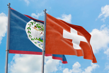 Switzerland and Belize flags waving in the wind against white cloudy blue sky together. Diplomacy concept, international relations.