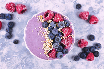 Top view of healthy yogurt and fruit smoothie bowl decorated with raspberry, blueberry and puffed...