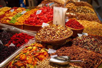 Delicious vibrant colored dried fruits and nuts variety in basktes on a food market stall: pistachios, almond, , close up
