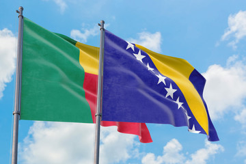 Bosnia Herzegovina and Benin flags waving in the wind against white cloudy blue sky together. Diplomacy concept, international relations.