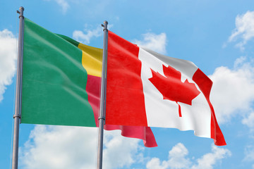 Canada and Benin flags waving in the wind against white cloudy blue sky together. Diplomacy...