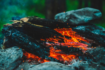 Vivid smoldered firewoods burned in fire close-up. Atmospheric warm background with orange flame of...