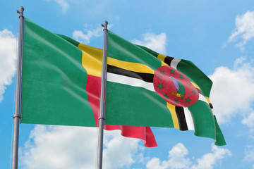 Dominica and Benin flags waving in the wind against white cloudy blue sky together. Diplomacy...
