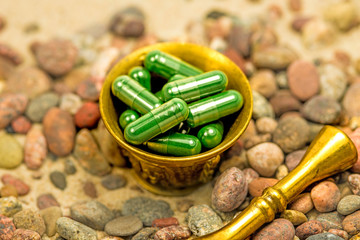 Spirulina capsules in a mortar on a beach with pebbles