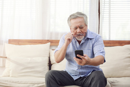 Older Men Move Glasses Down To Look At The Phone In The Hand Due To Hyperopia Problems, Which Makes Vision Difficult.Health Problems Of The Elderly.