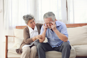 Retirement couples take care of each other when they are Alzheimer's Disease, sitting on the couch in the house. Ensuring mutual encouragement.