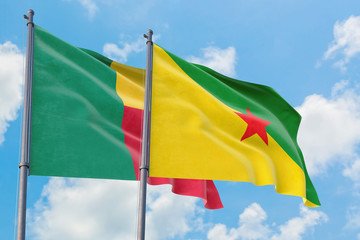 French Guiana and Benin flags waving in the wind against white cloudy blue sky together. Diplomacy concept, international relations.