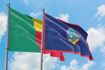 Guam and Benin flags waving in the wind against white cloudy blue sky together. Diplomacy concept, international relations.