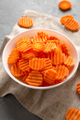 Fresh Raw Organic Carrot Chips in a bowl, side view. Close-up.