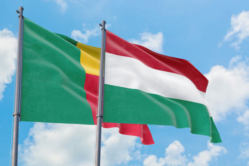 Fototapeta na wymiar Hungary and Benin flags waving in the wind against white cloudy blue sky together. Diplomacy concept, international relations.