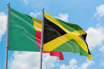Jamaica and Benin flags waving in the wind against white cloudy blue sky together. Diplomacy concept, international relations.