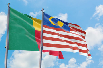 Malaysia and Benin flags waving in the wind against white cloudy blue sky together. Diplomacy concept, international relations.