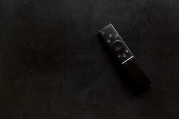 Television air recording concept. TV remote on black background top-down copy space