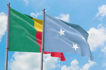 Micronesia and Benin flags waving in the wind against white cloudy blue sky together. Diplomacy concept, international relations.
