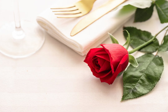 Red rose on white plate with gold cutlery. Saint valentines day celebration or romantic dinner concept.Toned image