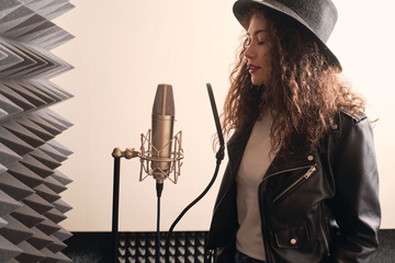 Pretty female singer recording in music studio