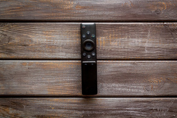 Television air recording concept. TV remote on dark wooden background top-down copy space