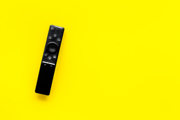Television air recording concept. TV remote on yellow background top-down copy space