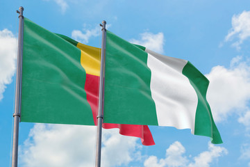 Nigeria and Benin flags waving in the wind against white cloudy blue sky together. Diplomacy concept, international relations.