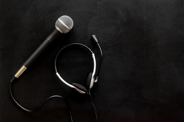 Television concept. Microphone and headset on black background top-down copy space