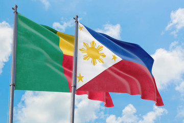 Philippines and Benin flags waving in the wind against white cloudy blue sky together. Diplomacy...