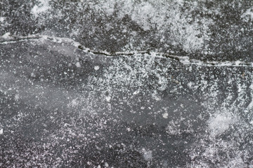Texutured ise surface of frozen lake. Close up. Scattered white snow around. Winter background.