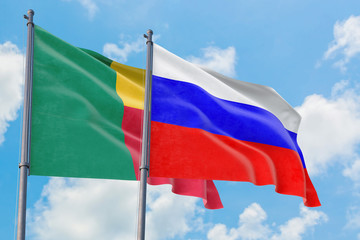 Russia and Benin flags waving in the wind against white cloudy blue sky together. Diplomacy concept, international relations.