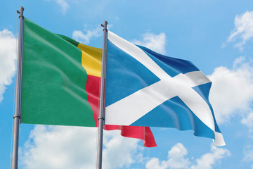 Scotland and Benin flags waving in the wind against white cloudy blue sky together. Diplomacy concept, international relations.