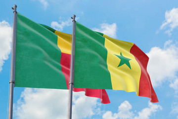 Senegal and Benin flags waving in the wind against white cloudy blue sky together. Diplomacy...