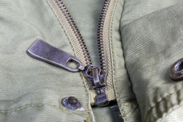 Slider of metal zipper on outerwear closeup in selective focus