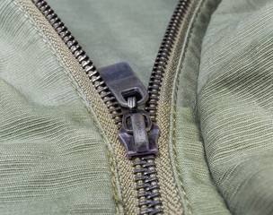 Fragment of metal zipper on outerwear olive color close-up