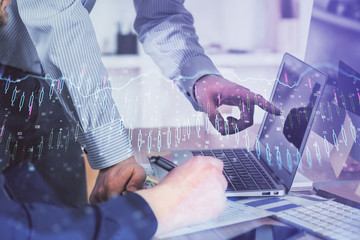 Double exposure of graph with man typing on computer in office on background. Concept of hard work. Closeup.