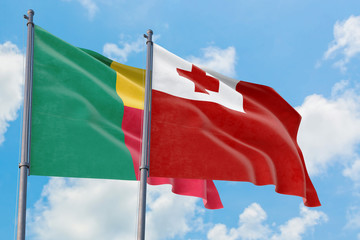 Tonga and Benin flags waving in the wind against white cloudy blue sky together. Diplomacy concept, international relations.