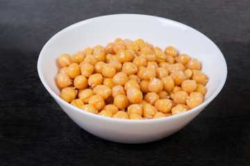 Boiled chickpeas in the white bowl on the black surface
