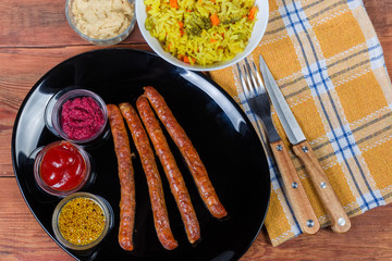 Baked pork sausages, condiments, rice with vegetables, fragment, top view