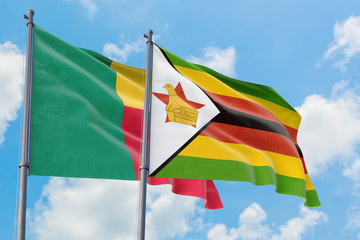 Zimbabwe and Benin flags waving in the wind against white cloudy blue sky together. Diplomacy concept, international relations.