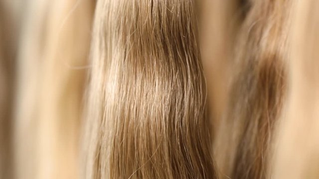 Long hair extensions in the salon close-up. Natural female hair, beautiful female hair.