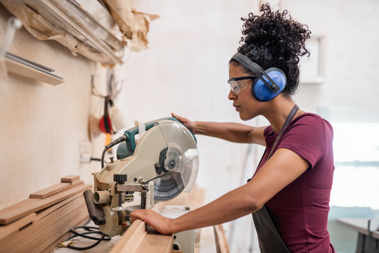 Female Artisan Cutting Wood In Her Framing Workshop