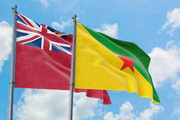 French Guiana and Bermuda flags waving in the wind against white cloudy blue sky together. Diplomacy concept, international relations.