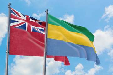 Gabon and Bermuda flags waving in the wind against white cloudy blue sky together. Diplomacy...