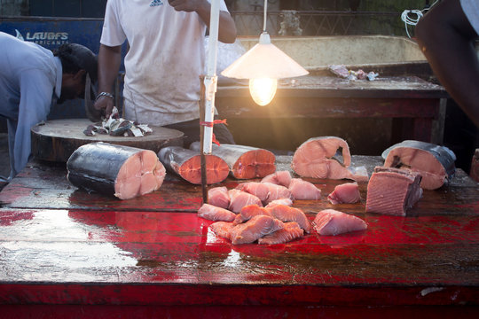 NEGOMBO, SRI LANKA - December 05, 2017. Fishermen are cutting fish on a red table.