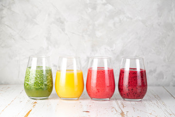 Selection of colorful smoothies and ingredients in glasses, rustic background