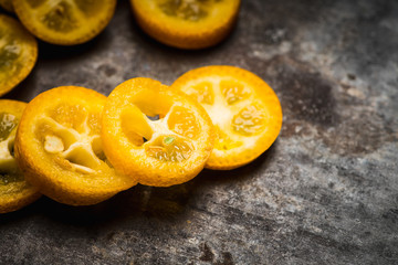 Sliced ripe kumquats on the rustic wooden background. Selective focus. Shallow depth of field.