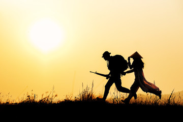 The silhouette of a soldier who led a young Vietnamese woman to escape the war at sunset