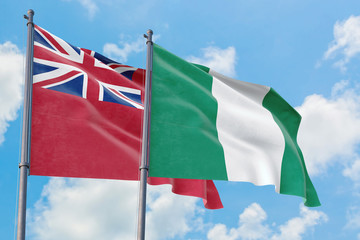 Nigeria and Bermuda flags waving in the wind against white cloudy blue sky together. Diplomacy concept, international relations.
