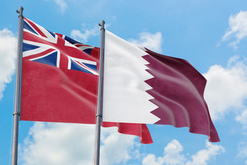 Qatar and Bermuda flags waving in the wind against white cloudy blue sky together. Diplomacy...