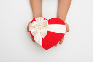 Children's hands hold gift box in the form of heart on white background. A concept by the Mother's Day.  Father's day. Birthday.