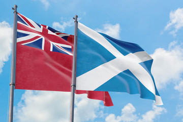 Scotland and Bermuda flags waving in the wind against white cloudy blue sky together. Diplomacy concept, international relations.